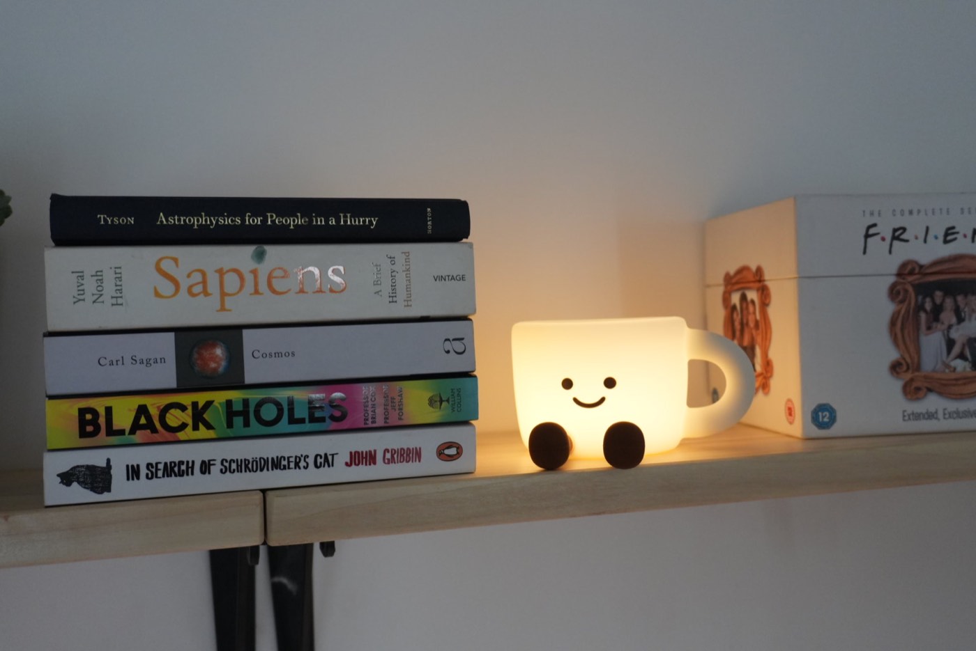 Books and a glowing coffee lamp styled on the wall shelf