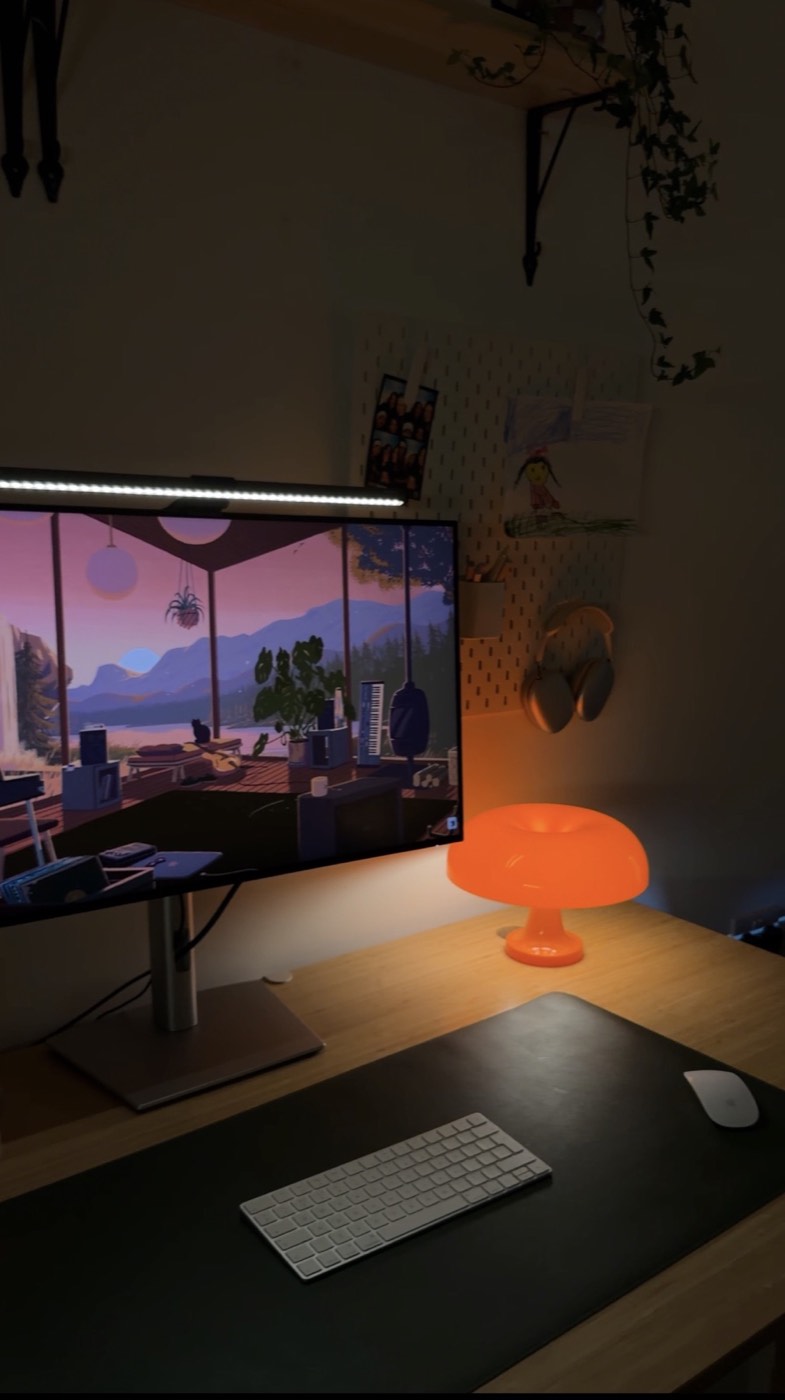 Desk monitor, light bar and orange mushroom lamp glowing at night
